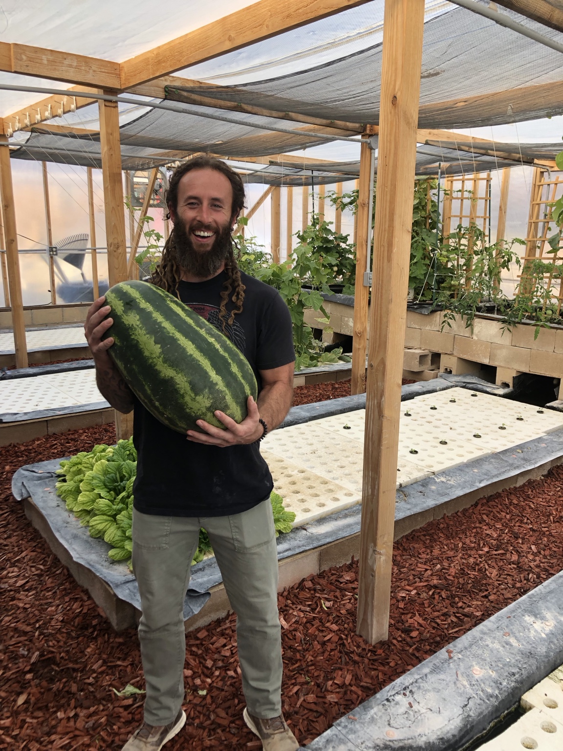 Robbie holding a watermelon inside his former greenhouse
